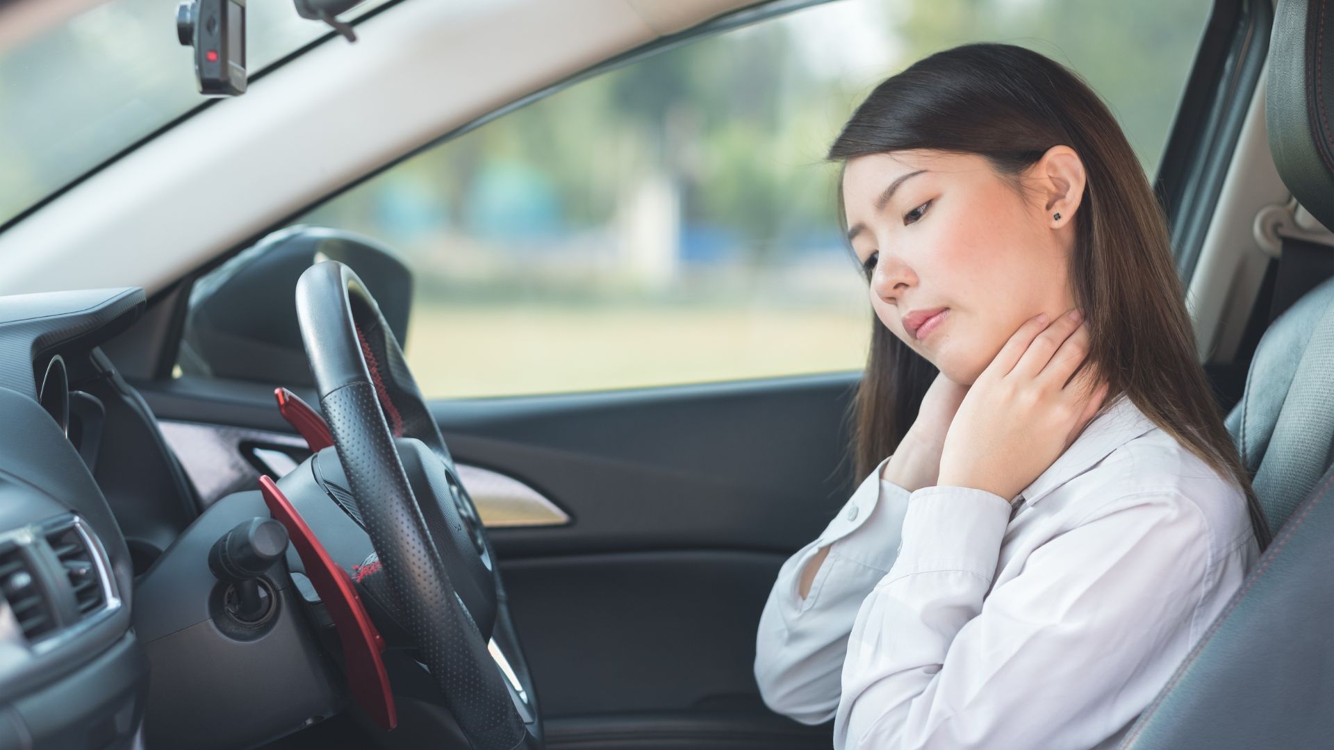 Woman holding her neck in pain while sitting in a car