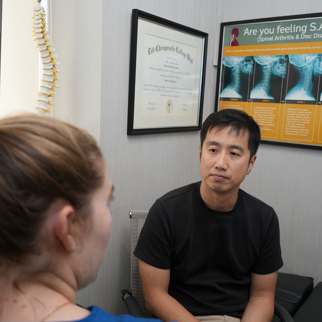 New patient discussing symptoms during a chiropractic consultation with a spine model at Healing Hands Chiropractic